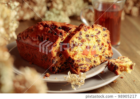 Fruit cake and tea on a wooden table with dried flowers. 98905217