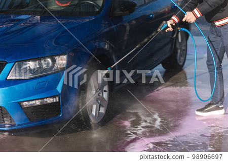 Process of cleaning car with a jet sprayer. Self service car washing. Close-up of man wash wheels Process of cleaning car with a jet sprayer. Self service car washing. Close-up of man wash wheels 98906697
