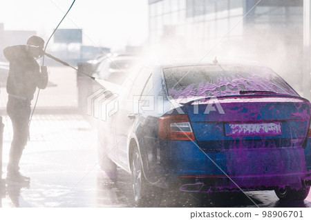 Process of man washing his car in a self-service car wash station. Back view Process of man washing his car in a self-service car wash station. Back view 98906701