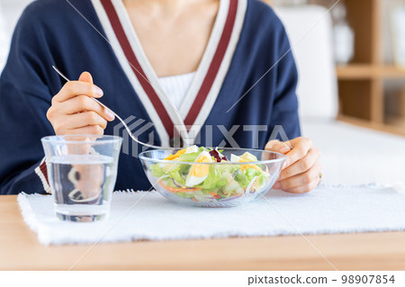 A young woman eating a salad 98907854