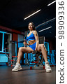 Beautiful woman pumps up lifts dumbbell exercise on bench in fitness gym 98909336