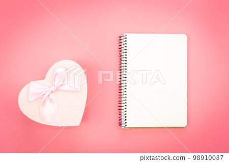 Blank notebook and heart shaped gift box on pink background, top view. 98910087