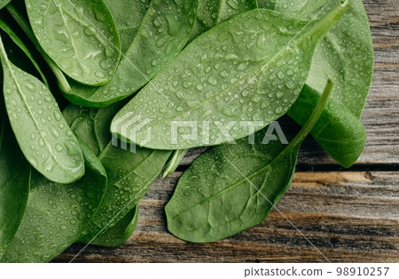 Wet fresh green baby spinach leaves on a wooden background. 98910257