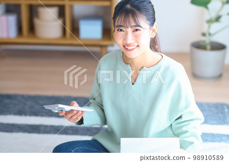 A young woman checking her luggage while looking at a calculator in her room A young woman checking her luggage while looking at a calculator in her room 98910589