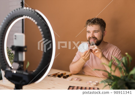 Portrait bearded man making vlog review cosmetics product and channel recording video make up tutorial making at home - Online influencer guy and social media market live steaming concept Portrait bearded man making vlog review cosmetics product and channel recording video make up tutorial making at home - Online influencer guy and social media market live steaming concept 98911341