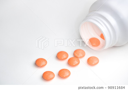 Spilled orange pills from open prescription medication plastic white bottle Spilled orange pills from open prescription medication plastic white bottle 98911684