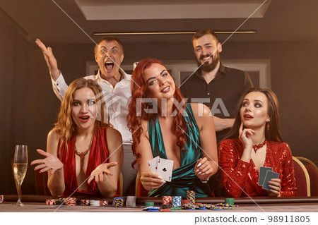 Group of a young wealthy friends are playing poker at a casino. 98911805