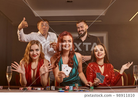 Group of a young wealthy friends are playing poker at a casino. Group of a young wealthy friends are playing poker at a casino. 98911810