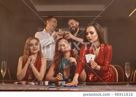 Group of a young wealthy friends are playing poker at a casino. 98911818