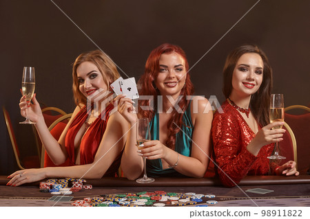 Three beautiful young women are playing poker at a casino. Three beautiful young women are playing poker at a casino. 98911822
