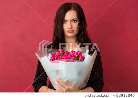 A beautiful young woman is holding a bouquet of pink roses A beautiful young woman is holding a bouquet of pink roses 98912846