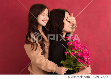 The girl greets her mother with a beautiful bouquet of pink roses The girl greets her mother with a beautiful bouquet of pink roses 98912854