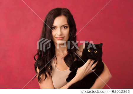 Beautiful woman holding a black cat Beautiful woman holding a black cat 98912855