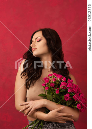 A beautiful woman is holding a bouquet of pink roses A beautiful woman is holding a bouquet of pink roses 98912856