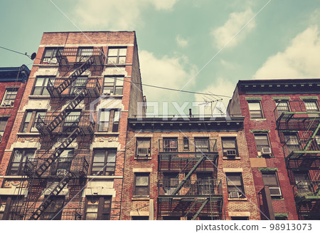 Old brick townhouses with fire escapes, color toning applied, New York City, USA. 98913073