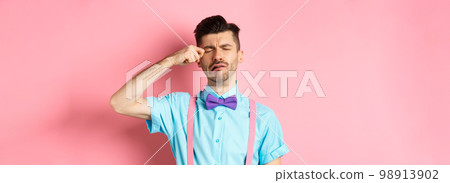 Image of heartbroken guy crying and wiping tear off face, sobbing and feeling sad or lonely, standing upset on pink background Image of heartbroken guy crying and wiping tear off face, sobbing and feeling sad or lonely, standing upset on pink background 98913902