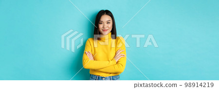 Attractive asian woman with short dark hair, cross arms on chest and smiling confident, standing over blue background Attractive asian woman with short dark hair, cross arms on chest and smiling confident, standing over blue background 98914219