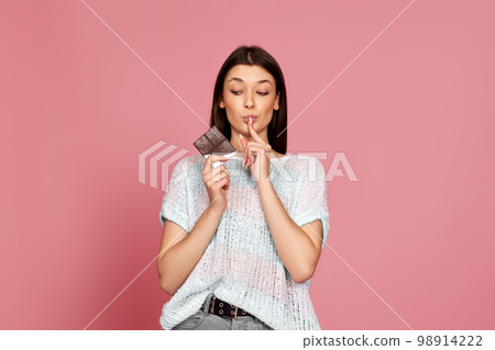 young woman in sweater holding chocolate bar 98914222
