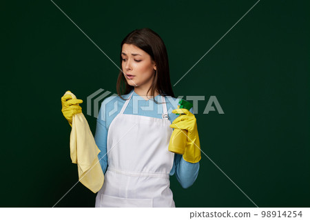 frowning woman cleaner apron with cleaning rag and detergent sprayer 98914254