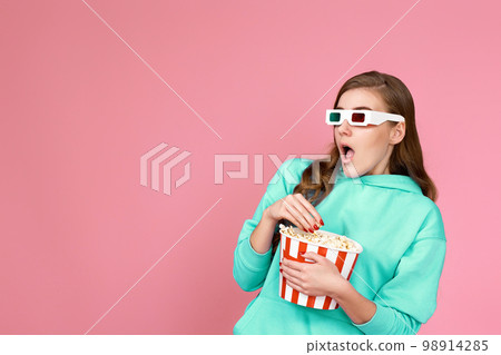 woman in sweatshirt holding bucket of popcorn woman in sweatshirt holding bucket of popcorn 98914285