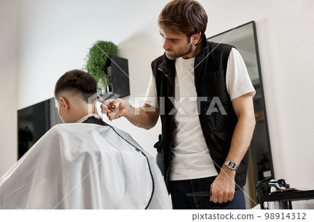 Professional hairdresser does haircut for caucasian bearded man Professional hairdresser does haircut for caucasian bearded man 98914312