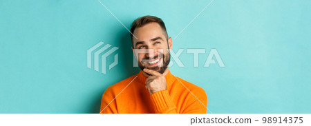 Close-up of caucasian male model having an idea, smiling and looking upper left corner thoughtful, imaging plan, standing over light blue background Close-up of caucasian male model having an idea, smiling and looking upper left corner thoughtful, imaging plan, standing over light blue background 98914375