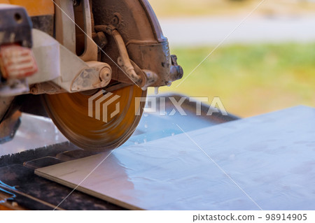 As part of preparation for laying floor tiles with assistance contractor tiles are cut into individual pieces to ease installation 98914905