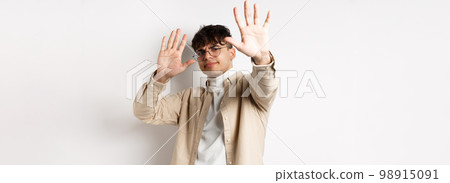 Image of reluctant and annoyed man raising hands up to block offer, refusing and asking to stop, telling no, declining something, standing on white background Image of reluctant and annoyed man raising hands up to block offer, refusing and asking to stop, telling no, declining something, standing on white background 98915091