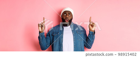 Disappointed african american guy complaining, looking and pointing fingers up at bad promo, standing displeased against pink background Disappointed african american guy complaining, looking and pointing fingers up at bad promo, standing displeased against pink background 98915402