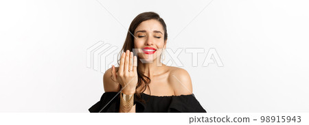 Happy young woman saying yes, become a bride, showing engagement ring on finger and smiling pleased, standing over white background Happy young woman saying yes, become a bride, showing engagement ring on finger and smiling pleased, standing over white background 98915943