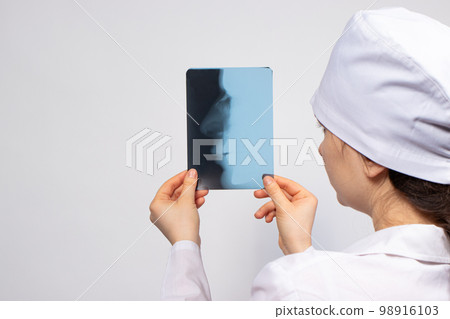 A doctor in white uniform examines an X-ray of a patient with a broken nose bone. Nose injury, crack or fracture - radiology and traumatology. 98916103