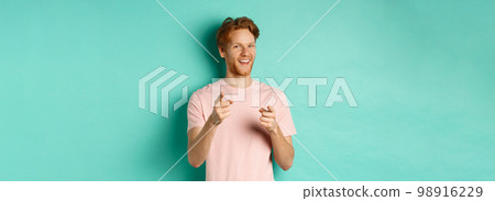 Funny redhead guy congratulating you, pointing fingers at camera and smiling, making choice, standing in t-shirt over mint background 98916229