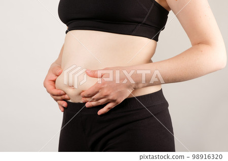 A woman shows an inflated thick belly, the concept of excess weight and weight loss. 98916320