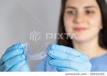 Doctor holding dental mouthguard, splint for the treatment of dysfunction of the temporomandibular joints, bruxism, malocclusion, to relax the muscles of the jaw. Doctor holding dental mouthguard, splint for the treatment of dysfunction of the temporomandibular joints, bruxism, malocclusion, to relax the muscles of the jaw. 98916409