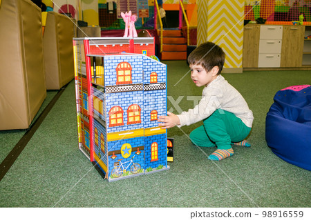 A 4-year-old boy plays in the playroom in the children's entertainment center with a toy big castle. A 4-year-old boy plays in the playroom in the children's entertainment center with a toy big castle. 98916559