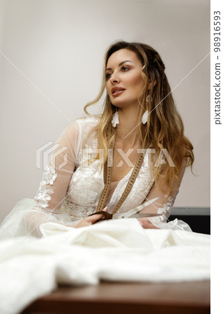 A girl in a boho wedding dress in a sewing workshop. 98916593