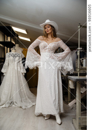 A girl in a boho wedding dress in a sewing workshop. 98916605