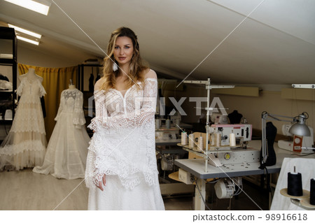 A girl in a boho wedding dress in a sewing workshop. 98916618
