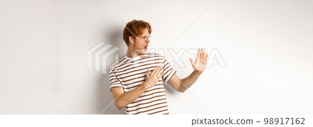 Funny redhead man standing in martial arts pose, fighting shadow and looking left, standing over white background Funny redhead man standing in martial arts pose, fighting shadow and looking left, standing over white background 98917162