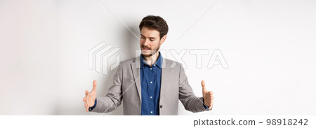 Excited handsome businessman showing long size thing, big object with stretch out hands, standing in suit on white background 98918242