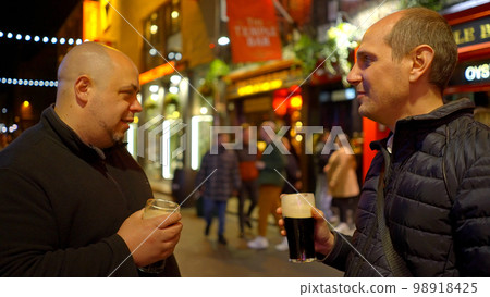 Guys drinking a beer in the Temple Bar district of Dublin by night - travel photography Guys drinking a beer in the Temple Bar district of Dublin by night - travel photography 98918425