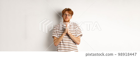Cute redhead man in glasses asking for help, pleading and looking clingy at camera, begging for favour, white background Cute redhead man in glasses asking for help, pleading and looking clingy at camera, begging for favour, white background 98918447