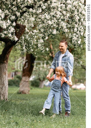 Dad and daughter are hugging under an apple blossom tree. 98918561