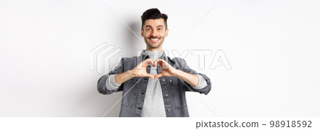 Handsome man showing heart gesture and smiling. Romantic guy say I love you and smiling tender at camera. Valentines day concept Handsome man showing heart gesture and smiling. Romantic guy say I love you and smiling tender at camera. Valentines day concept 98918592