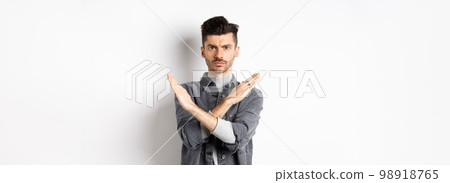 Angry man show cross gesture to stop or say no, frowning and looking serious, disagree and prohibit bad situation, standing on white background Angry man show cross gesture to stop or say no, frowning and looking serious, disagree and prohibit bad situation, standing on white background 98918765