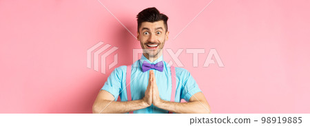 Image of smiling young man asking please, looking grateful at camera, Guy in bow-tie say thank you, standing over pink background 98919885