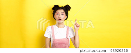 Excited teen asian girl having idea, raising finger and say suggestion, wearing stylish summer clothes with makeup, yellow background Excited teen asian girl having idea, raising finger and say suggestion, wearing stylish summer clothes with makeup, yellow background 98920216