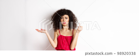 Sad girlfriend with curly hair, showing finger without ring and look confused, complaining at indecisive boyfriend, wanting to get married, standing on white background Sad girlfriend with curly hair, showing finger without ring and look confused, complaining at indecisive boyfriend, wanting to get married, standing on white background 98920338