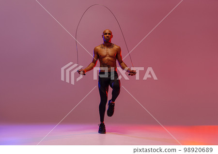 Man skipping with jump rope on studio background. Strength and motivation. Best cardio workout Man skipping with jump rope on studio background. Strength and motivation. Best cardio workout 98920689