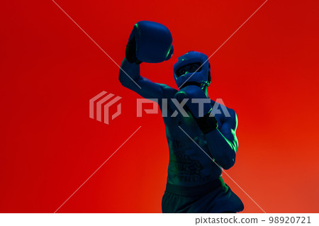 Sporty man wearing head guard and boxing gloves practicing for fight on studio background Sporty man wearing head guard and boxing gloves practicing for fight on studio background 98920721